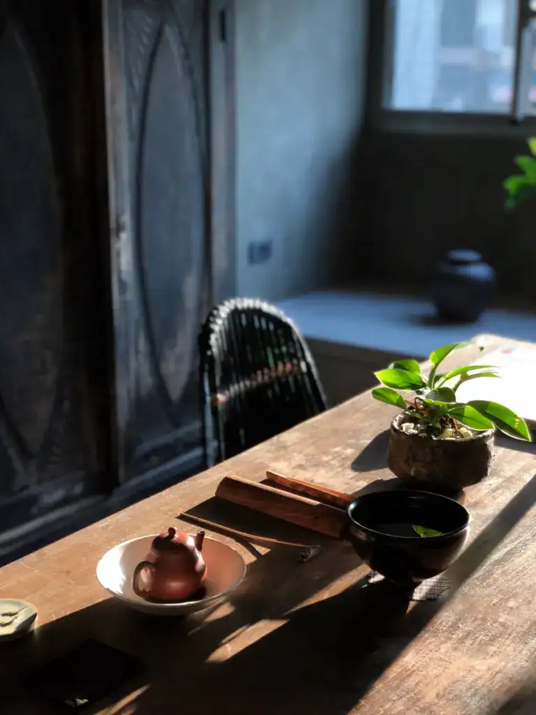 木質長桌搭配復古茶具與自然光影，呈現易介對材質細節與溫潤空間氛圍的掌握。